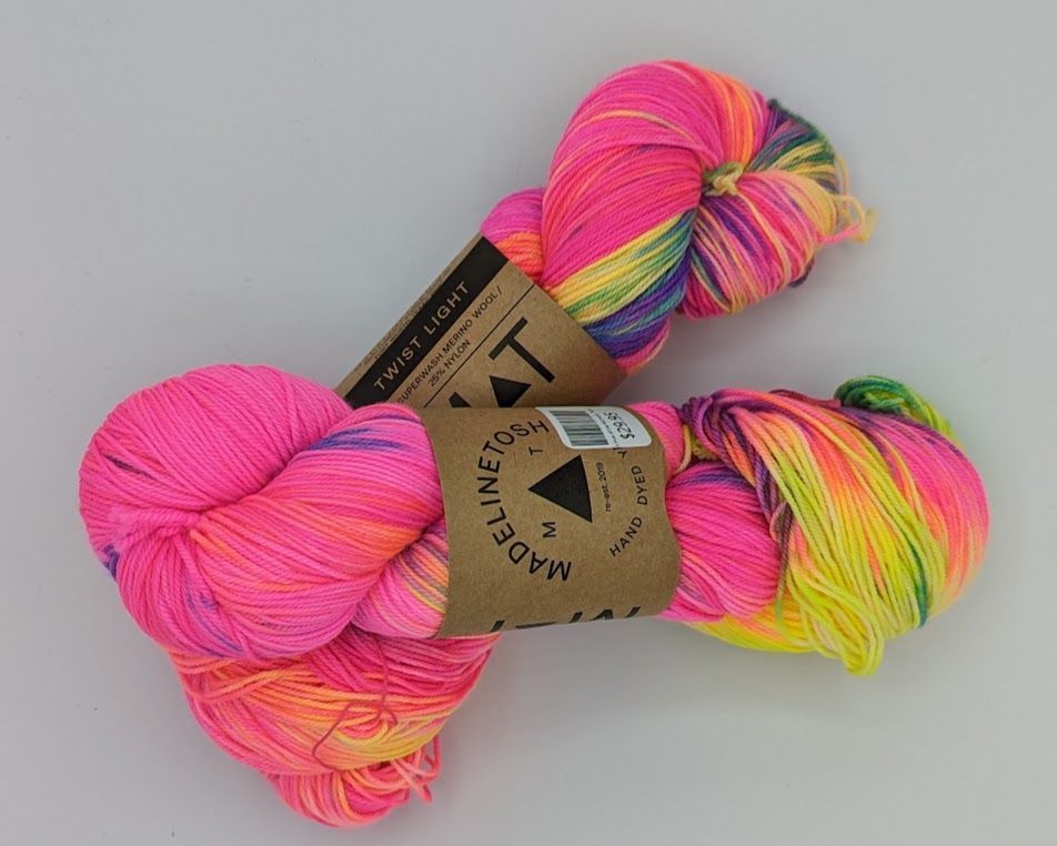 Two skeins of hot pink yarn with yellow, purple, and green highlights.
